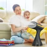 Fier de călcat vertical Glissio utilizat acasă de familie, eliminând cutele rapid și sigur pentru hainele copiilor.