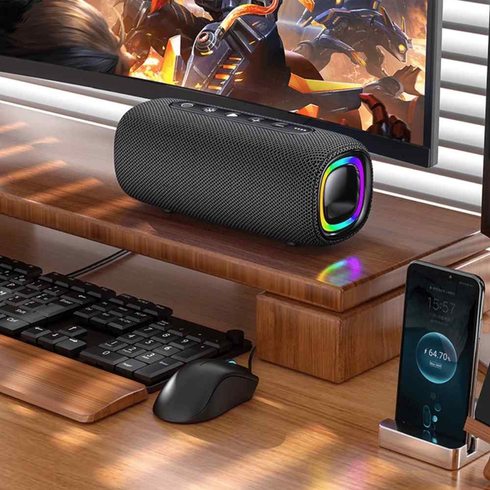 Boxă portabilă cu inel RGB așezată pe birou, lângă monitor, tastatură, mouse și telefon