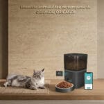 Hrănitor automat PAWTY pentru pisici, controlat din aplicație, prezentat într-un living alături de telefonul mobil.